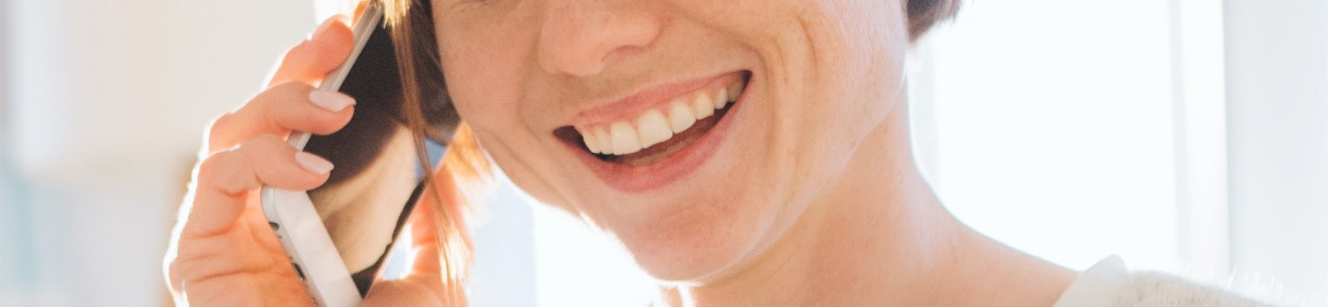 Close-up of a smiling person holding a phone to their ear, engaged in a conversation